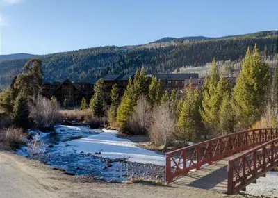 a bridge over a river with snow and trees at Slopeside by Summit County Mountain Retreats in Keystone