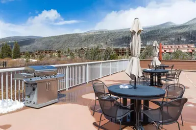 a patio with tables and chairs and a grill at Slopeside by Summit County Mountain Retreats in Keystone