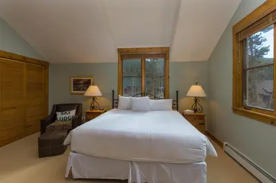 a bedroom with a large white bed and a chair at Ski Tip by Summit County Mountain Retreats in Keystone