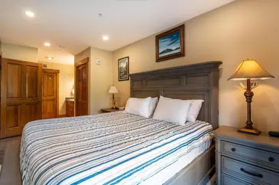 a bedroom with a bed and a lamp on a dresser at Springs by Summit County Mountain Retreats in Keystone