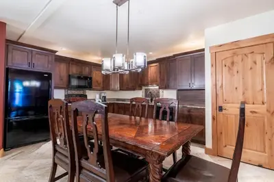 a kitchen with a wooden table with chairs and a refrigerator at Tenderfoot Lodge by Summit County Mountain Retreats in Keystone