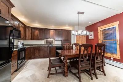a kitchen with wooden cabinets and a wooden table and chairs at Tenderfoot Lodge by Summit County Mountain Retreats in Keystone
