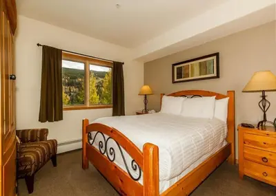 a bedroom with a bed and a chair and a window at Gateway by Summit County Mountain Retreats in Keystone
