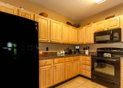 a kitchen with wooden cabinets and a black refrigerator at Gateway by Summit County Mountain Retreats in Keystone