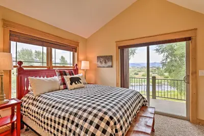 a bedroom with a bed and a large window at Fish, Hike and Ski Riverfront Granby Cabin! in Granby