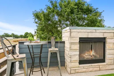 a fireplace on a patio with a table and chairs at Old Town Modern New Build - Rooftop Spa with Mtn Views! in Fort Collins