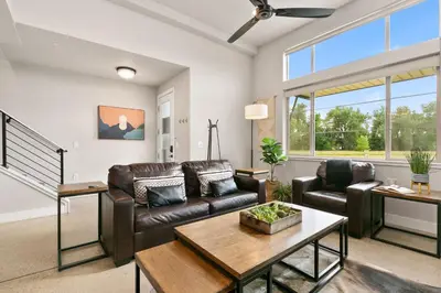 a living room with a leather couch and a table at Old Town Modern New Build - Rooftop Spa with Mtn Views! in Fort Collins