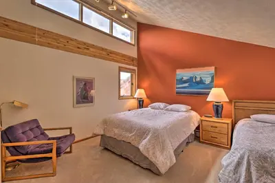 a bedroom with two beds and a chair and a window at Resort Perks and Trail Access Silverthorne Condo! in Silverthorne