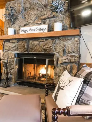 a living room with a stone fireplace and a couch at Riverfront Mountain Cottage Retreat in Estes Park