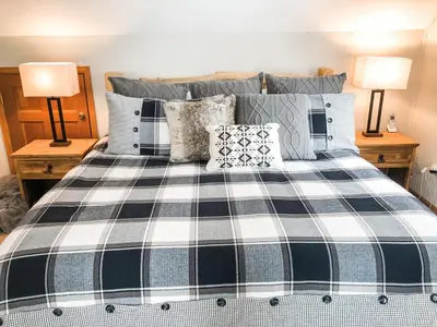 a bedroom with a black and white bed with two lamps at Riverfront Mountain Cottage Retreat in Estes Park