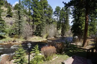 a river in a forest with a street light and trees at Riverfront Mountain Cottage Retreat in Estes Park