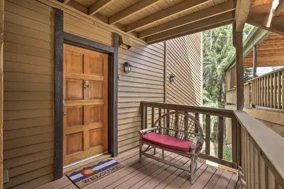 a porch with a wooden door and a bench at Cozy Condo on Vasquez Creek with Free Shuttle Access in Winter Park