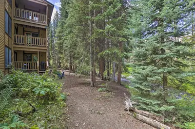 a path in the woods next to a building at Cozy Condo on Vasquez Creek with Free Shuttle Access in Winter Park