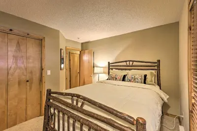 a bedroom with a wooden bed and a wooden door at Cozy Condo on Vasquez Creek with Free Shuttle Access in Winter Park