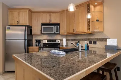 a kitchen with a granite counter top and a refrigerator at Iron Horse C5083 condo in Winter Park