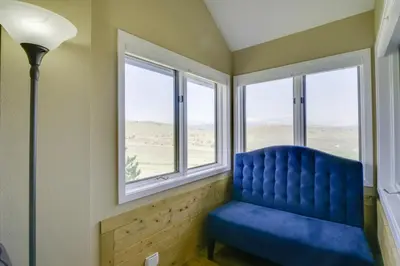 a blue chair in a room with windows at Walk to Ski Lifts Mtn-View Granby Retreat! in Granby