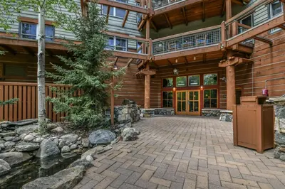 an exterior view of a log cabin with a pond and patio at Jackpine Lodge 2 Bedroom Condo in Keystone