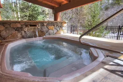 a hot tub in a patio with a stone wall at Jackpine Lodge 2 Bedroom Condo in Keystone