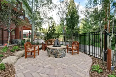 a patio with three chairs and a statue in front of a fence at Jackpine Lodge 2 Bedroom Condo in Keystone