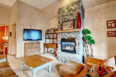 a living room with a stone fireplace and a tv at Black Bear Lodge 3 Bedroom Condo In River Run Village in Keystone
