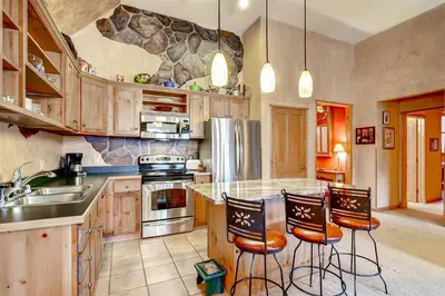 a kitchen with wooden cabinets and a counter with bar stools at Black Bear Lodge 3 Bedroom Condo In River Run Village in Keystone