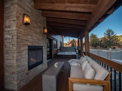 a living room with a fireplace on a deck at Beautiful Views! Jacuzzi, Indoor/ Outdoor Fireplace, Steps to Lake Estes in Estes Park