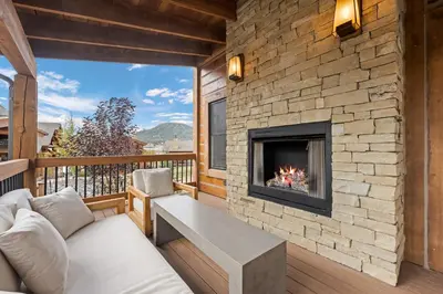 a living room with a fireplace on a deck at Beautiful Views! Jacuzzi, Indoor/ Outdoor Fireplace, Steps to Lake Estes in Estes Park
