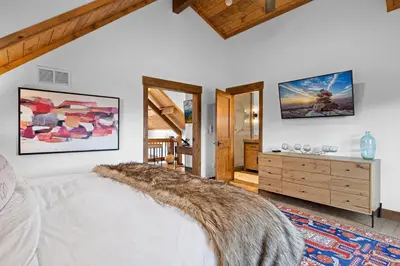 a bedroom with a large white bed and a dresser at Beautiful Views! Jacuzzi, Indoor/ Outdoor Fireplace, Steps to Lake Estes in Estes Park