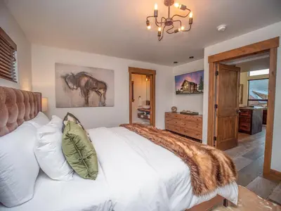 a bedroom with a large white bed and a chandelier at Relax in Luxury - Jacuzzi, Indoor/Outdoor Fireplace in Estes Park