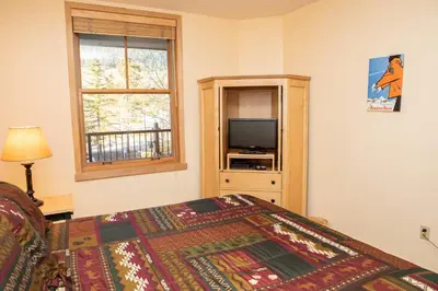 a bedroom with a bed and a tv and a window at 8176 Silver Mill condo in Keystone
