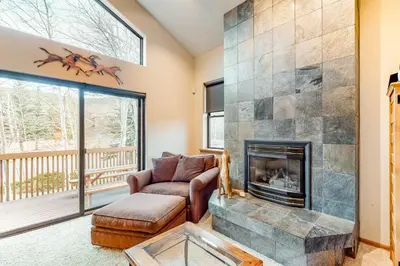 a living room with a fireplace and a chair at Dawn's Cabin in Frisco