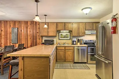 a kitchen with wooden cabinets and a stainless steel refrigerator at Cozy Ski Chalet Less Than 3 Mi to Winter Park Resort! in Winter Park