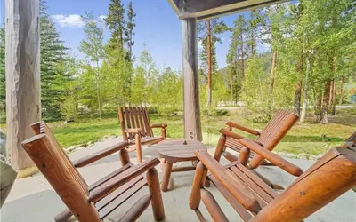 three wooden chairs and a table on a porch at 8750 Trappers Crossing condo in Keystone