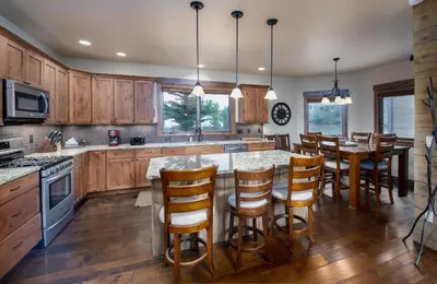 a kitchen with wooden cabinets and a island with bar stools at Ridgeview Court Townhome: Incredible Rooftop Deck in Frisco