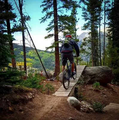 a man riding a bike on a wooden trail at Tarn Landing Condo: Access To All Summit Resorts in Frisco