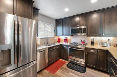 a kitchen with wooden cabinets and stainless steel appliances at Blue Granite Off Main Townhome: Updated, Great Location in Frisco