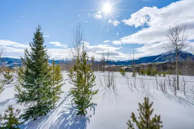 a snowy field with trees and the sun in the sky at 8 Mi to Keystone Mtn-View Ski Retreat! in Silverthorne