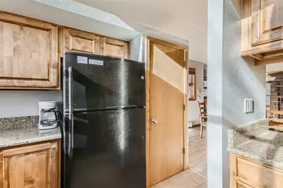 a kitchen with a black refrigerator and wooden cabinets at Cabin Creek Condos C-1 condo in Frisco