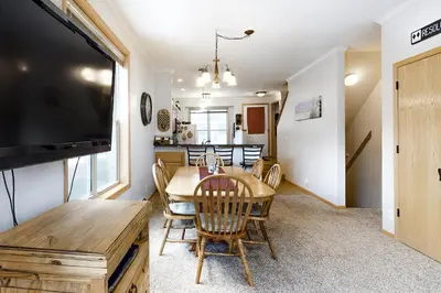 a dining room with a table with chairs and a flat screen tv at Saddle Ridge in Silverthorne