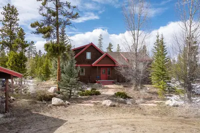 a home with a red house in the woods at 383 County Road 508 by Stay Winter Park in Fraser