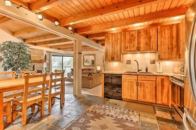 a kitchen with wooden cabinets and a table and chairs at Ski and Hike Mtn-View Condo in Silverthorne! in Silverthorne