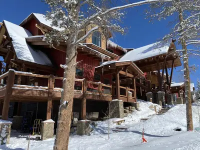 a large log cabin with snow on the ground at The Seasons 1818 condo in Keystone