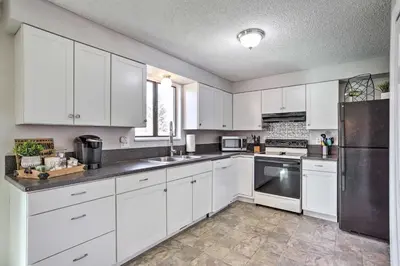 a kitchen with white cabinets and a stainless steel refrigerator at Duplex with Private Yard 3 Mi to Downtown Loveland! in Loveland