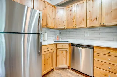 a kitchen with a stainless steel refrigerator and wooden cabinets at 2 Blocks to Main St Downtown Frisco Condo! in Frisco