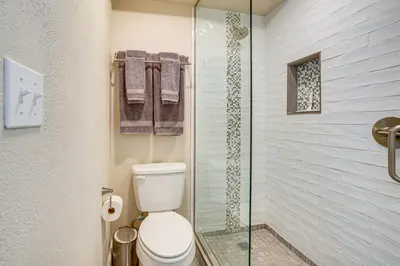 a bathroom with a toilet and a glass shower at 2 Blocks to Main St Downtown Frisco Condo! in Frisco