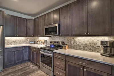 a kitchen with wooden cabinets and a stove top oven at Ski and Hike Home with Hot Tub and Gas Grill in Granby in Granby