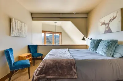 a bedroom with a bed and two blue chairs at Mountain Adventure Home Base - Ski, Hike and Chill! in Fraser