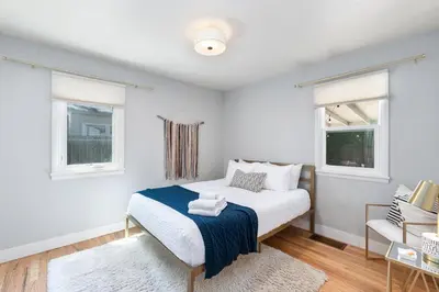 a white bedroom with a bed and two windows at Fun, Family-Friendly Old Town Home with Hot Tub! in Fort Collins