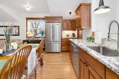 a kitchen with wooden cabinets and a stainless steel refrigerator at The Beautiful Bears Den! Walk to Old Town and CSU! in Fort Collins