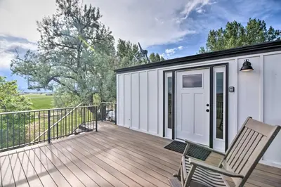 a deck with a door and two chairs on it at Lovely Barn Loft with Mountain Views on Horse Estate in Fort Collins